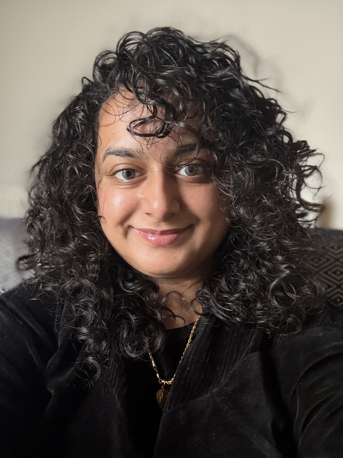 Portrait of Priyaneet Kainth, smiling warmly.